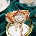 Macro detail of luxury gold quartz bracelet watch with red rhinestones and tassels - Red Zircon