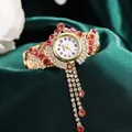 Macro detail of luxury gold quartz watch with white dial and red rhinestone tassels - Pink Rhinestone