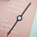 Detail of quartz watch with black mesh strap and rhinestone bezel on pink background - Black