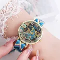 Detailaufnahme einer Boho-Uhr mit gewebtem Armband und goldenem Zifferblatt am Handgelenk - Stil H