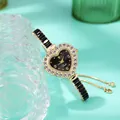 Detail of heart-shaped gold watch with rhinestone bezel and black dial on green background - Gold Black