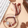 Detail van een handgeweven etnisch horloge met glanzende strassteentjes op hout - Zwart