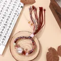 Macro-opname van een etnisch handgeweven horloge met strass-bezel en kleurrijke kwastjes - Wit