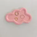 Dreiteiliges Gold-Ohrklemmen- und Ring-Set auf einer rosa wolkenförmigen Schmuckschale - Rosa Wolke