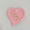 Nahaufnahme von Perlenohrring und Ring auf einem rosa herzförmigen Harztablett als Deko - Rosa Herz
