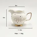 Detailed view of white ceramic milk pitcher with black polka dots and gold trim handle - White Dots (Milk)