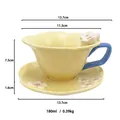 Pale yellow ceramic coffee cup with blue handle and 3D white flower detail with saucer - Yellow