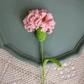 Detail of hand-knitted pink carnation crochet flower on a lace tablecloth for gifts - Pink