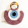 Handgefertigte Häkeltasche mit Evil Eye Motiv und bernsteinfarbenen Harzgriffen - Lila