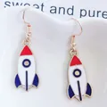 Detalle de pendientes de cohete en rojo, blanco y azul sobre una bandeja de cerámica - Estilo de Cohete Animado (EAR1198-1)