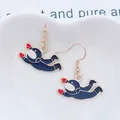 Vista macro de pendientes de astronauta en una bandeja de cerámica blanca con forma corazón - Estilo de Colgante Astronauta (EAR1198-4)