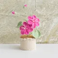 Handmade knitted potted plant with pink crochet flowers and green leaves on white base - Tung Flower Rose Red