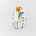Close-up of handmade crochet orange tulip with green stem and Love Is Eternal ribbon - Orange