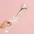 Handmade crochet white tulip flower in gift bag with beige love ribbon on pink background - Tulip White