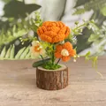 Handgehäkelte orangefarbene Rose im Naturholzstamm-Topf für die Tischdekoration - Orange Rose