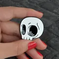 Primo piano della spilla smaltata a teschio tenuta in mano per riferimento dimensioni - Stile Testa di Scheletro (XZ0467)
