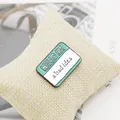 Macro shot of Hello I'm a Bad Idea enamel pin on a textured fabric background - Mint Green Bad Idea Name Tag (XZ1109)