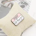Close-up of pink enamel name tag pin featuring HELLO I'M Cuter than you text on burlap - Pink Cuter Than You Name Tag (XZ1110)
