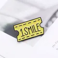 Detail of yellow enamel movie ticket brooch with Smile text and black metal border - Yellow Smile Style (XZ0797)