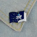 Astronaut flying in space book enamel pin badge attached to blue denim fabric - Astronaut Book Style (XZ1217)