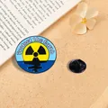 Detailansicht einer Emaille-Anstecknadel mit dem Text Protect the Earth und Strahlenwarnsymbol - A19-6-896