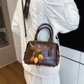 Retro dunkelbraune Boston Tasche aus Leder mit Blatt-Anhänger auf weißem Strickpullover - Mit Anhänger / Kaffeebraun