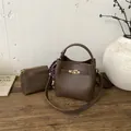 Secchiello marrone in pelle a grana con foulard e chiusura dorata su fondo in legno - Marrone