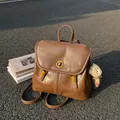 Vintage brown leather backpack with metal twist lock and cute bear charm outdoor view - With Pendant / Brown