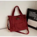 Deep red canvas tote bag featuring top handles and a brown leather logo patch - Burgundy