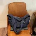 Borsa a tracolla blu scuro minimalista in nylon imbottito su una sedia di legno - Blu Notte