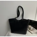 Minimalist black PU leather tote bag shown with laptop and books for daily commute - Black