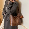 Vintage brown leather hobo bag with teddy bear charm shown on a stylish model - With Pendant / Brown