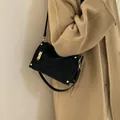 Borsa a tracolla vintage nera con borchie dorate indossata su un cappotto - Nero
