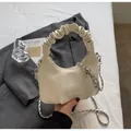 Detail of a creamy white pleated handbag on grey fabric with a silver logo and chain strap - Off-White No Charm
