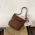 Borsa a secchiello in pelle cerata marrone con chiusura metallica dorata e tracolla - Caffè senza Ciondolo