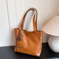 Borsa tote caramello con etichetta fashion e ciondolo a pretzel marrone in set studio - Borsa Singola / Marrone