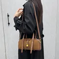 Sac Boston marron en mélange de cuir suédé avec cadenas doré, porté par un mannequin - Marron