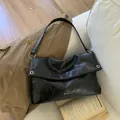 Minimalist black wrinkled leather tote bag with silver ring detail on a neutral trench coat - Black - Without Pendant