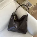 Dark brown Hobo tote bag with metallic eyelets and bohemian bead charm on sofa - Coffee With Pendant