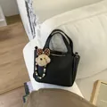 Black lychee texture bucket bag with puppy charm on white fabric sofa background - With Pendant / Black