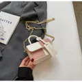 Detail der zweifarbigen Mini-Handtasche mit goldener Kette auf einem stilvollen Blazer - Klein / Gebrochenes Weiß
