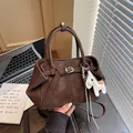 Elegante braune Handtasche mit Pferdeanhänger in gemütlicher Büroumgebung - Mit Anhänger(20650) / Braun