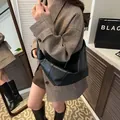 Bolso bandolera de media luna negro minimalista con detalles anudados y una chaqueta - Negro