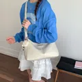 Chic cream white pleated tote bag with plush charm shown on a casual model outfit - Off White
