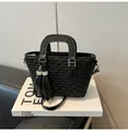 Chic black bucket bag with pleated texture and rhinestone tassels on a stylish book - Black