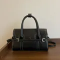 Chic black leather handbag with white contrast stitching and golden hardware buckle - Black