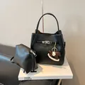 Bolso tipo cubo de cuero granulado negro con cierre giratorio plateado y colgante - Sin Colgante Con Bolsa / Negro