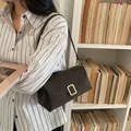 Sac bandoulière rétro marron foncé en cuir mat avec boucle dorée sur chemise rayée - café