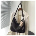Borsa tote minimalista marrone scuro con ciondolo a orsetto su sfondo beige - Caffè Con Pendente