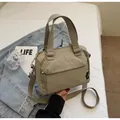 Gros plan d'un sac seau en nylon kaki avec de larges poignées et finitions argent - Kaki